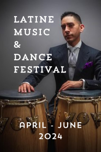 Latine Music & Dance Festival April-June 2024. Image of Luis Armacanqui wearing a suit and tie and drumming on two tall wooden hand drums.