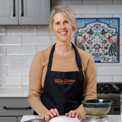 Nicole Bujewski standing in a kitchen wearing an apron